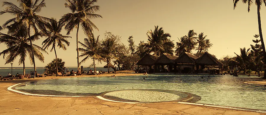 Piscina de hotel cercada por coqueiros
